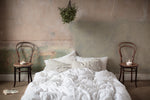 Bare stripped walls and soft linen bedding 